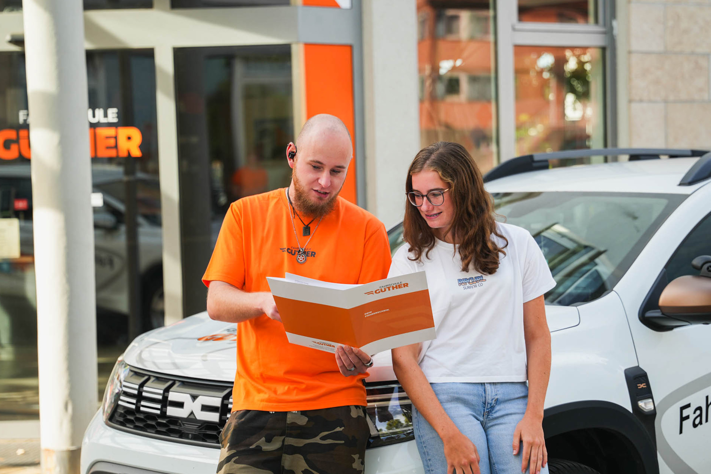 Fahrlehrer mit Fahrschülerin vor der Filiale Rommelsbach